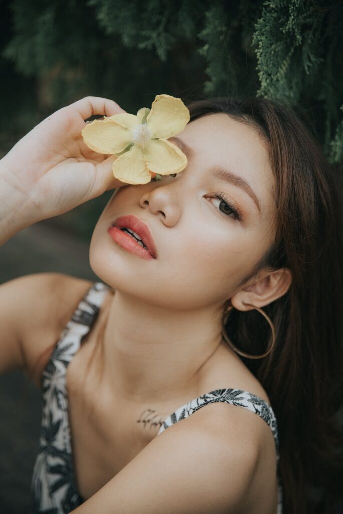 trendy asian woman covering eye with flower
